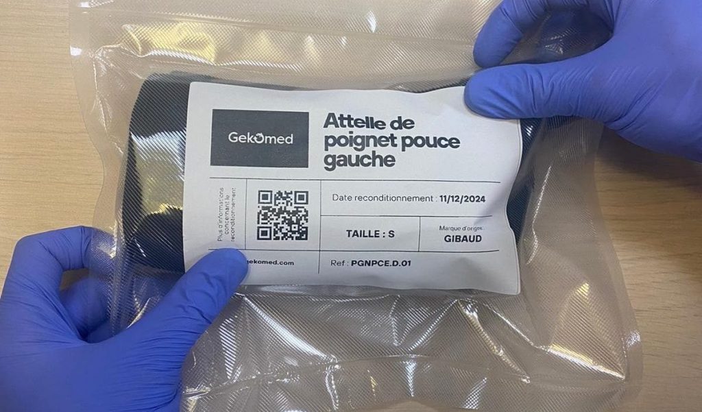 Attelle de poignet reconditionnée Gekomed, emballée sous sachet scellé et étiquetée avec QR code et informations de traçabilité, tenue par des gants médicaux.